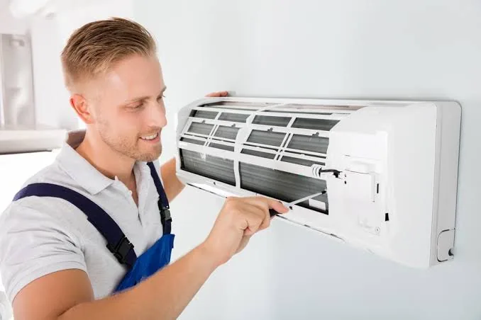 Technician inspecting an open indoor air conditioning unit during installation