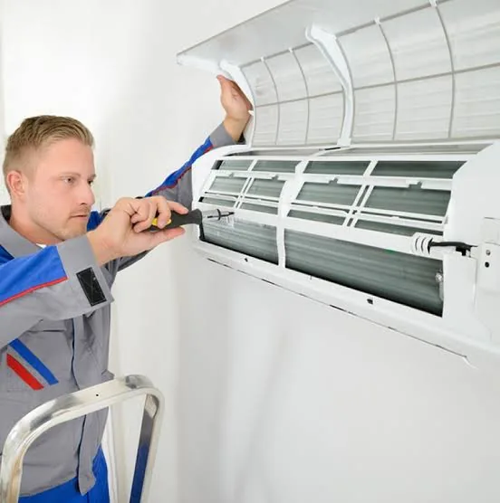Technician servicing a wall-mounted indoor air conditioner