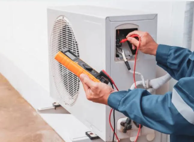 Technician testing electrical connections on an outdoor air conditioner