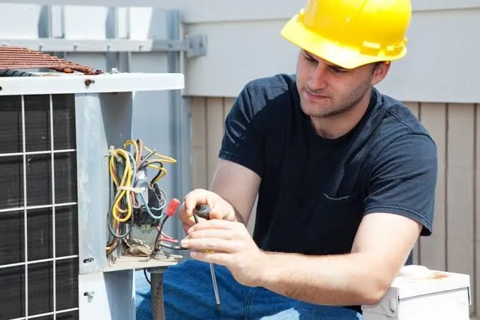 Technician repairing electrical connections on an outdoor HVAC unit