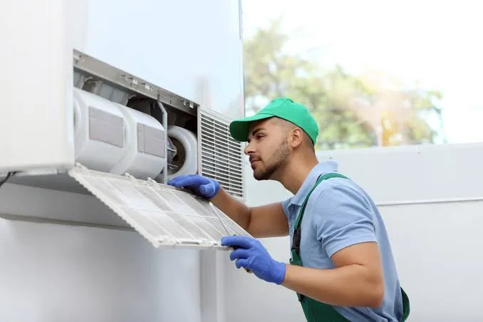 Technician checking an outdoor HVAC unit filter